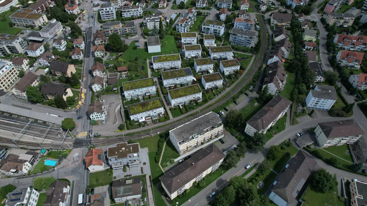 Luftaufnahme auf das Zentrum von Hinwil mit dem Bahnübergang beim Bahnhof.
